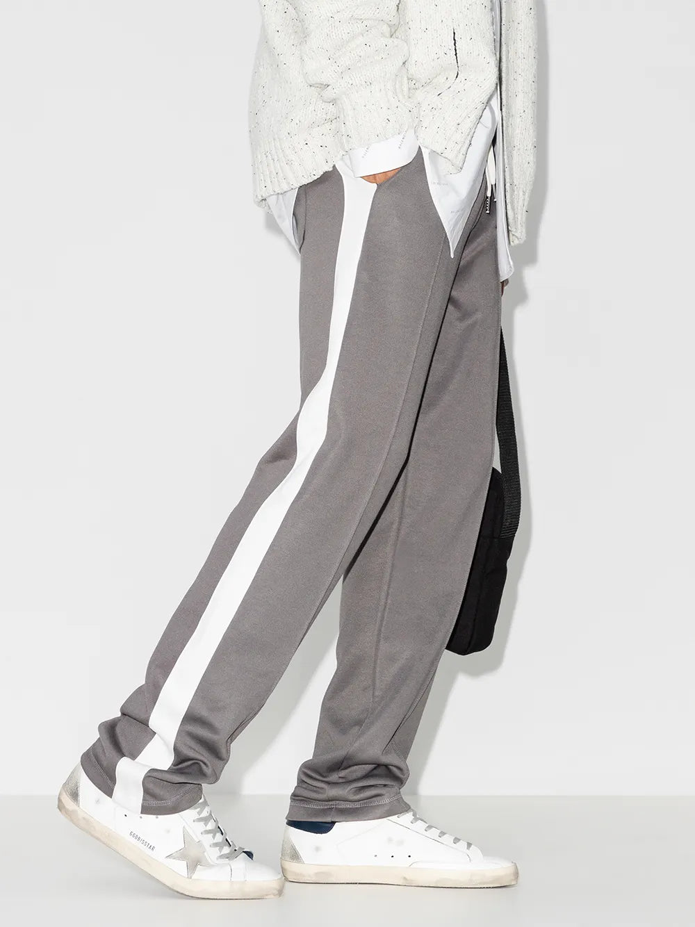 White low-top sneakers worn with gray pants and lace-up design