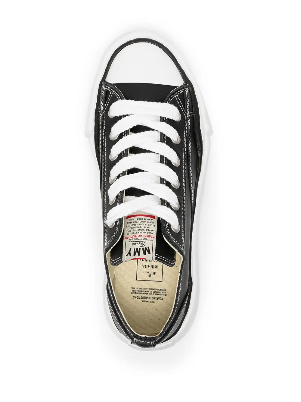 Black low-top sneakers, white laces, and inner label visible near the opening