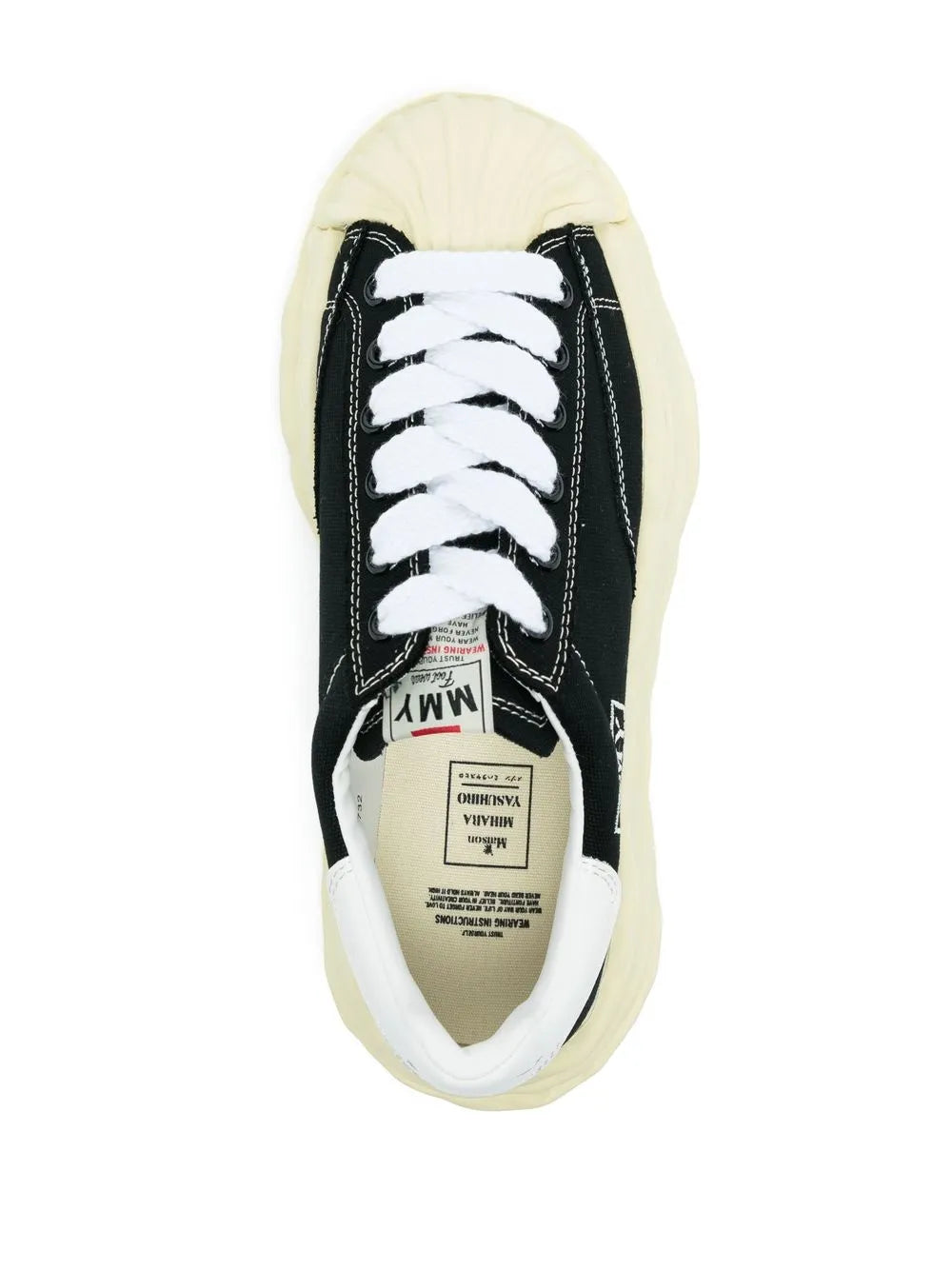Black low-top sneaker with white laces, visible tongue label, cream gum sole