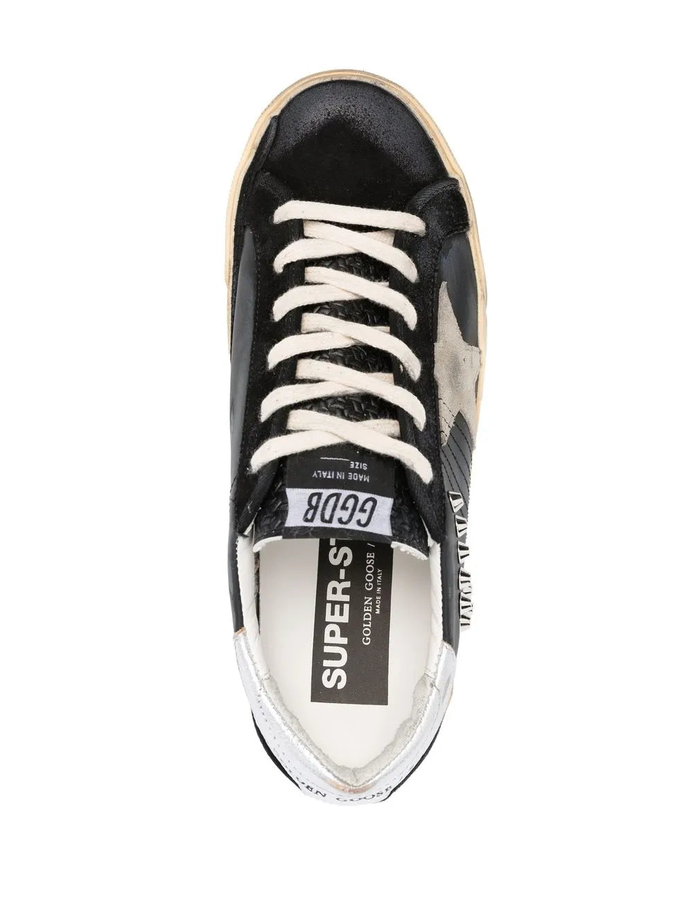 Black low-top sneakers with white laces, cushioned tongue label, tan rubber sole.