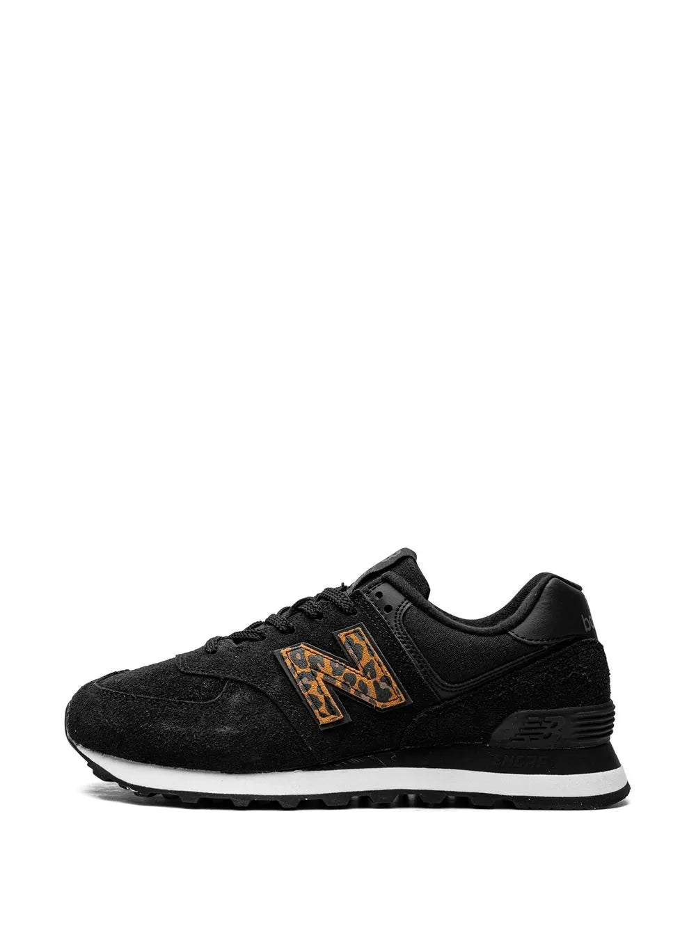 New Balance 574 sneaker in black, side view with orange patterned logo and laces