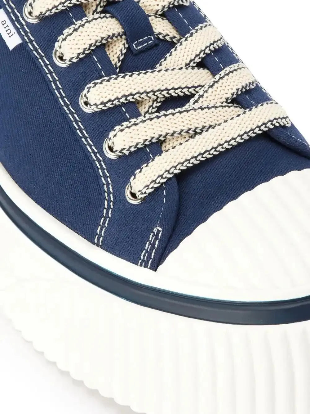 Close-up of dark blue sneaker lace-up with cream woven laces and eyelets
