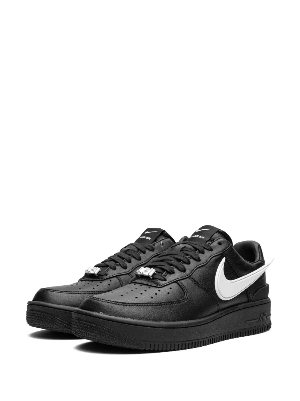 Black low-top sneakers with white swoosh, lace-up closure, perforated leather upper