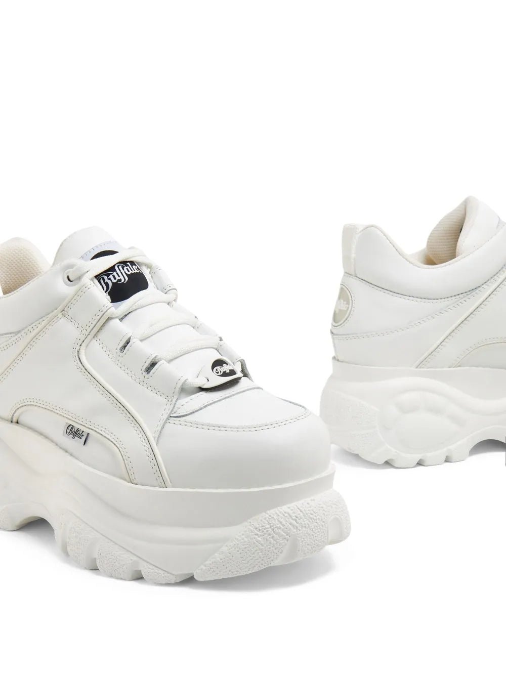 Close-up of white low-top lace sneakers with thick sole tread and eyelets