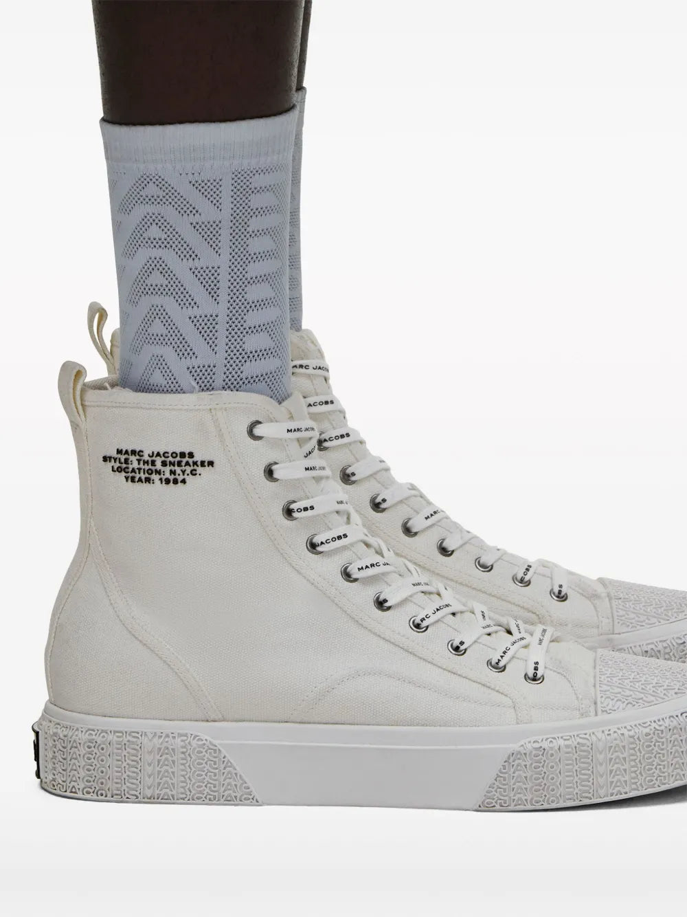 White high-top canvas sneaker with lace-up front and logo text on tongue