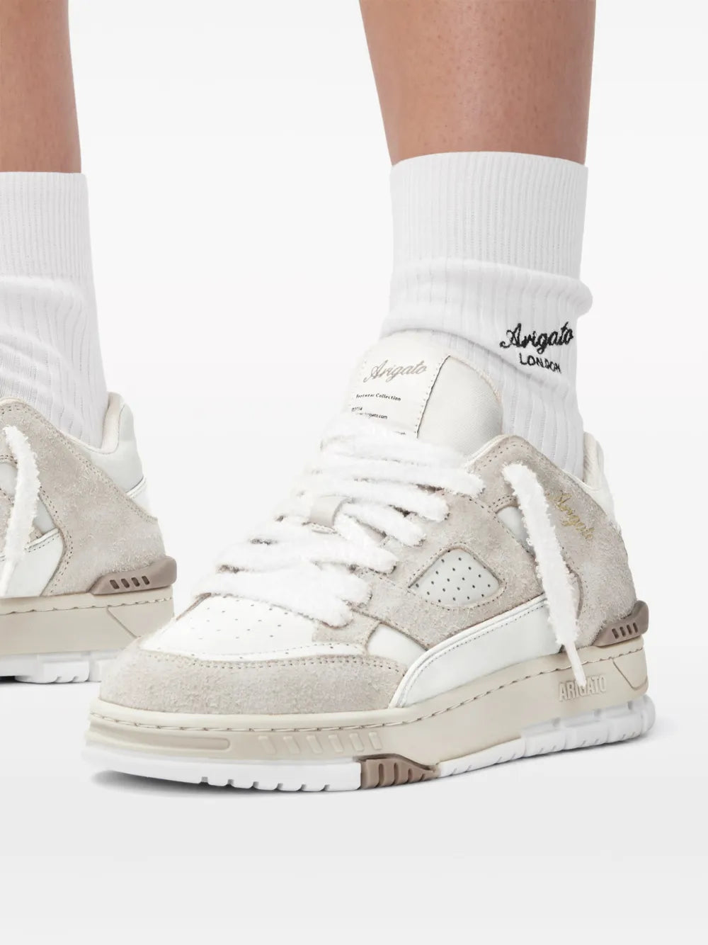 Beige and white sneakers worn with white crew socks, lace-up design and chunky sole.