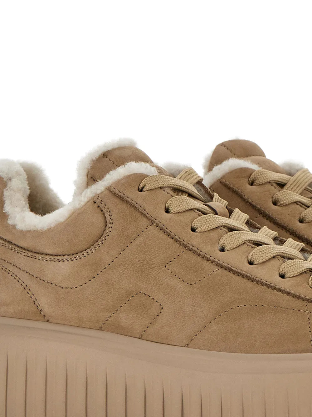 Close-up of tan suede lace-up sneakers with sherpa collar and perforated detail