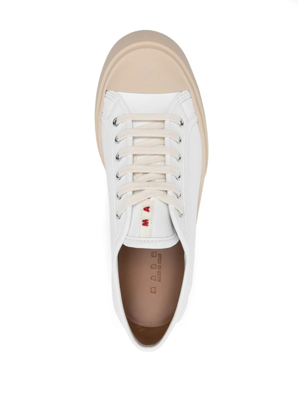 Lace-up sneaker with white upper, beige lining, and visible insole text