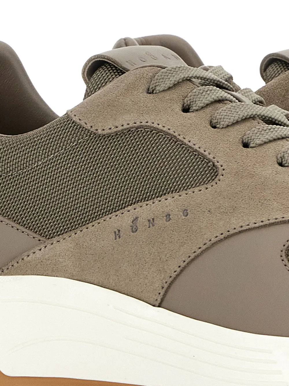Close-up of taupe and olive sneaker upper with suede paneling and lace detail