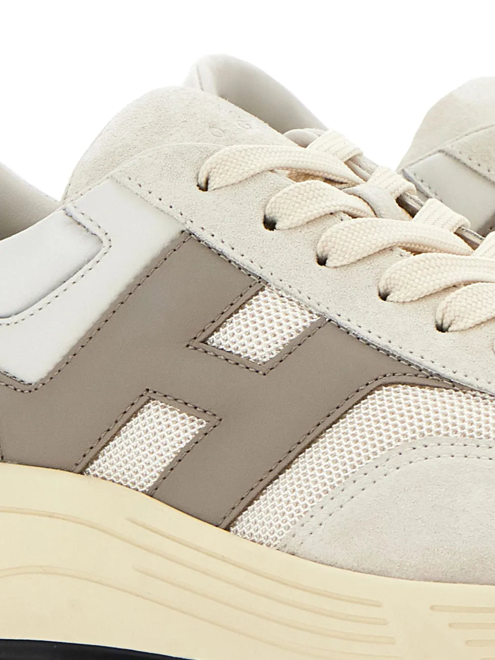 Beige sneaker upper close-up with perforated side panels and lace eyelets.