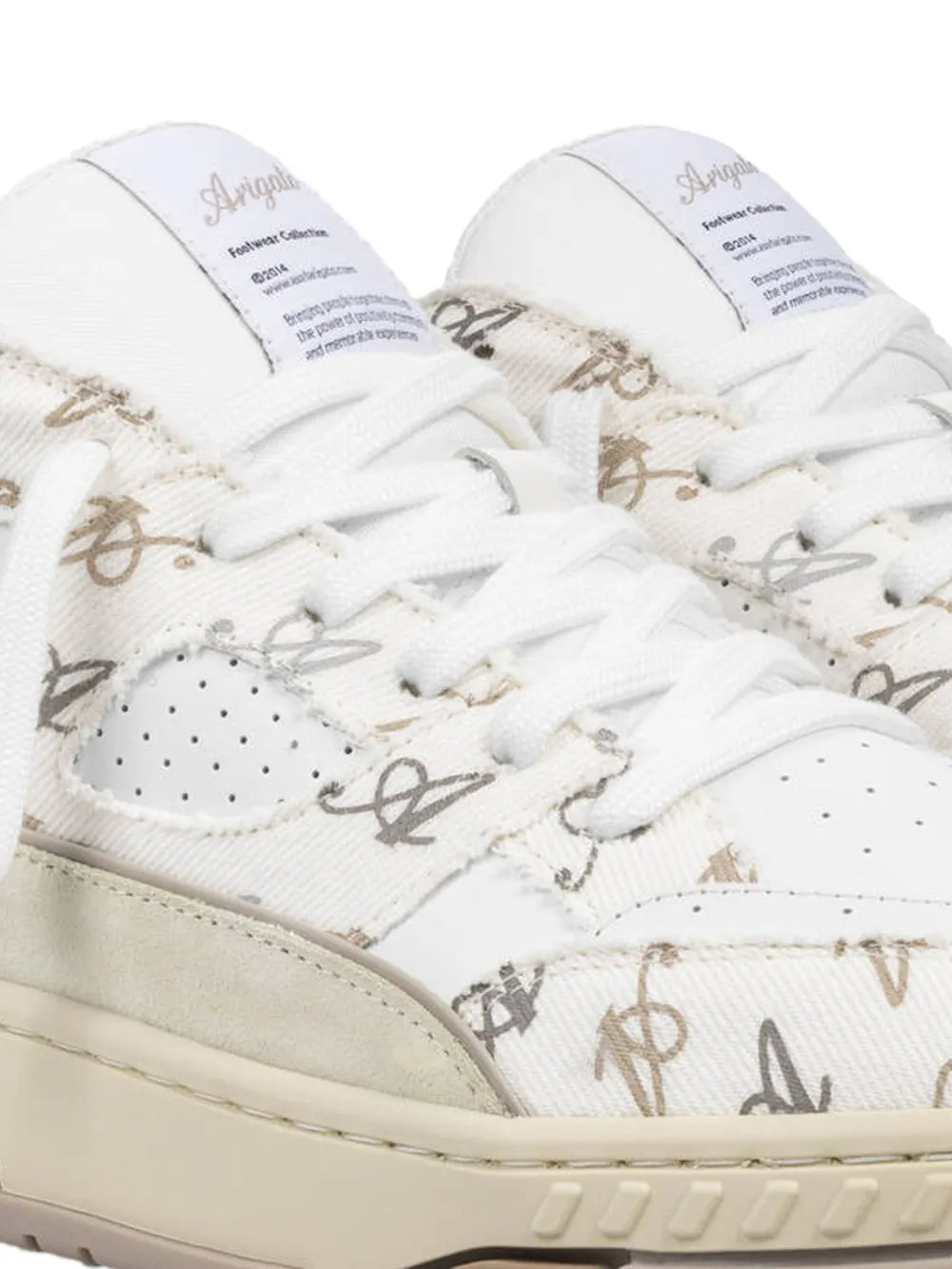 Axel Arigato monogram sneakers close-up: patterned upper, white laces, eyelets.