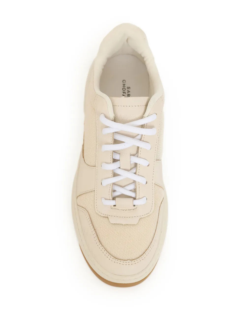 Beige sneaker close-up with white lace-up front and stitched overlays