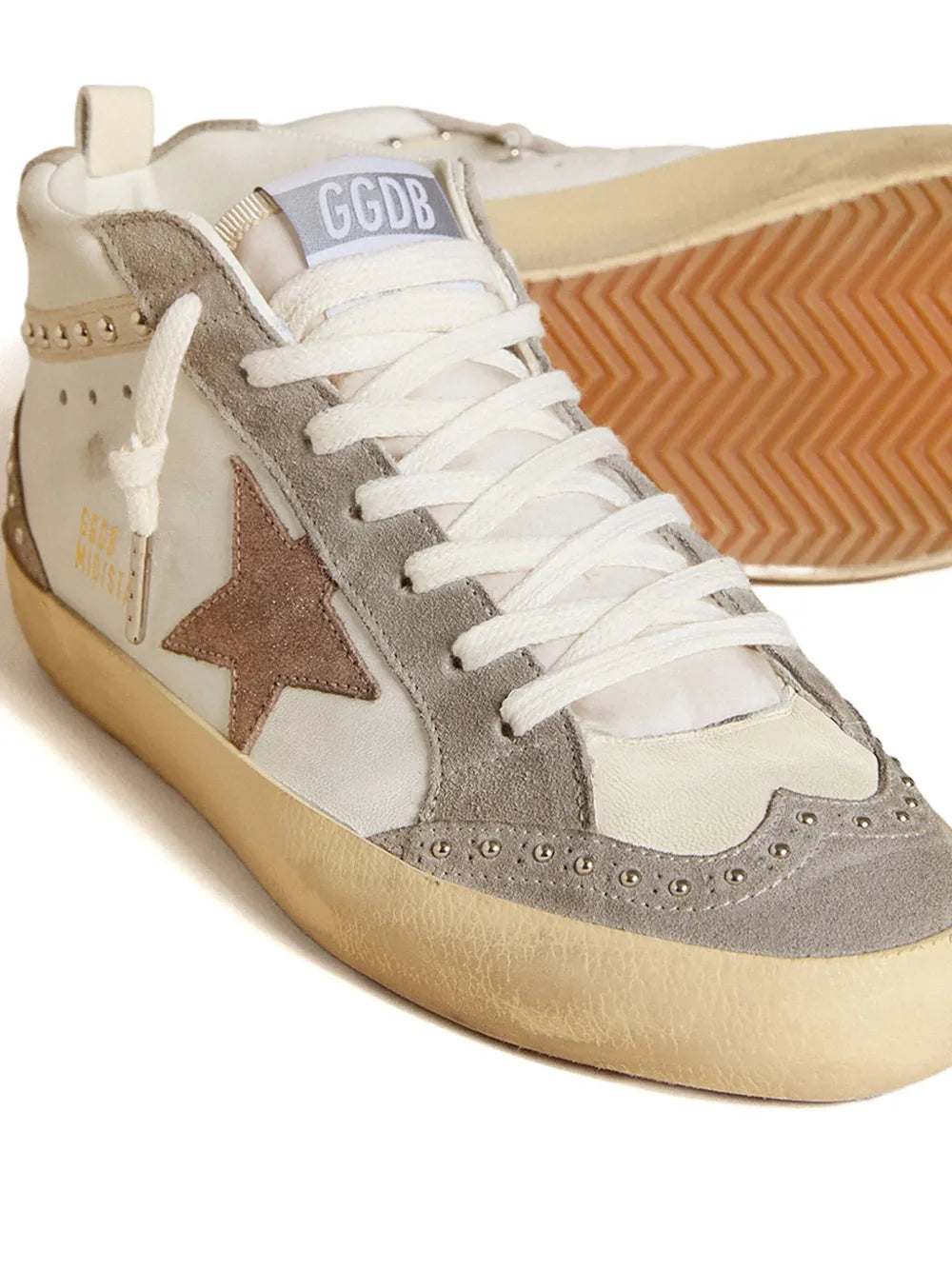 Mid-top sneaker close-up, gray suede star, white laces, studded trim, tan sole