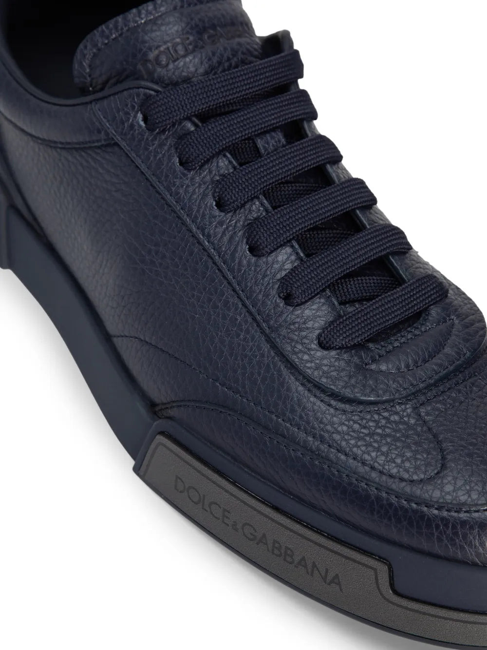 Dark blue leather sneaker close-up, lace-up and side logo on rubber sole