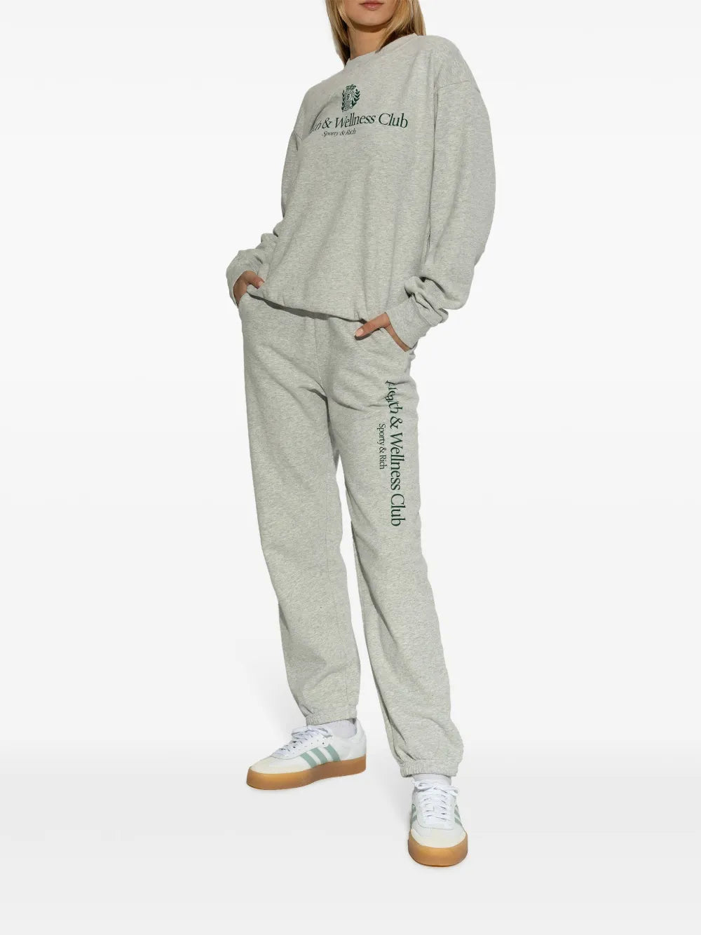 White low-top sneakers with mint stripes and gum sole worn with gray tracksuit