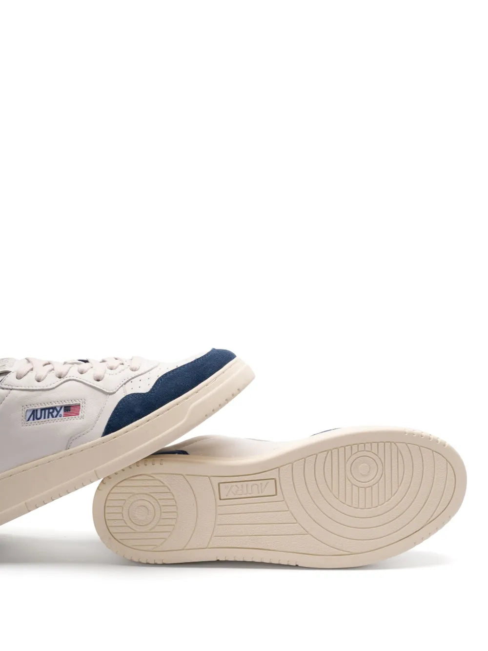 Low-top sneaker outsole in tan with textured tread on white and navy pair