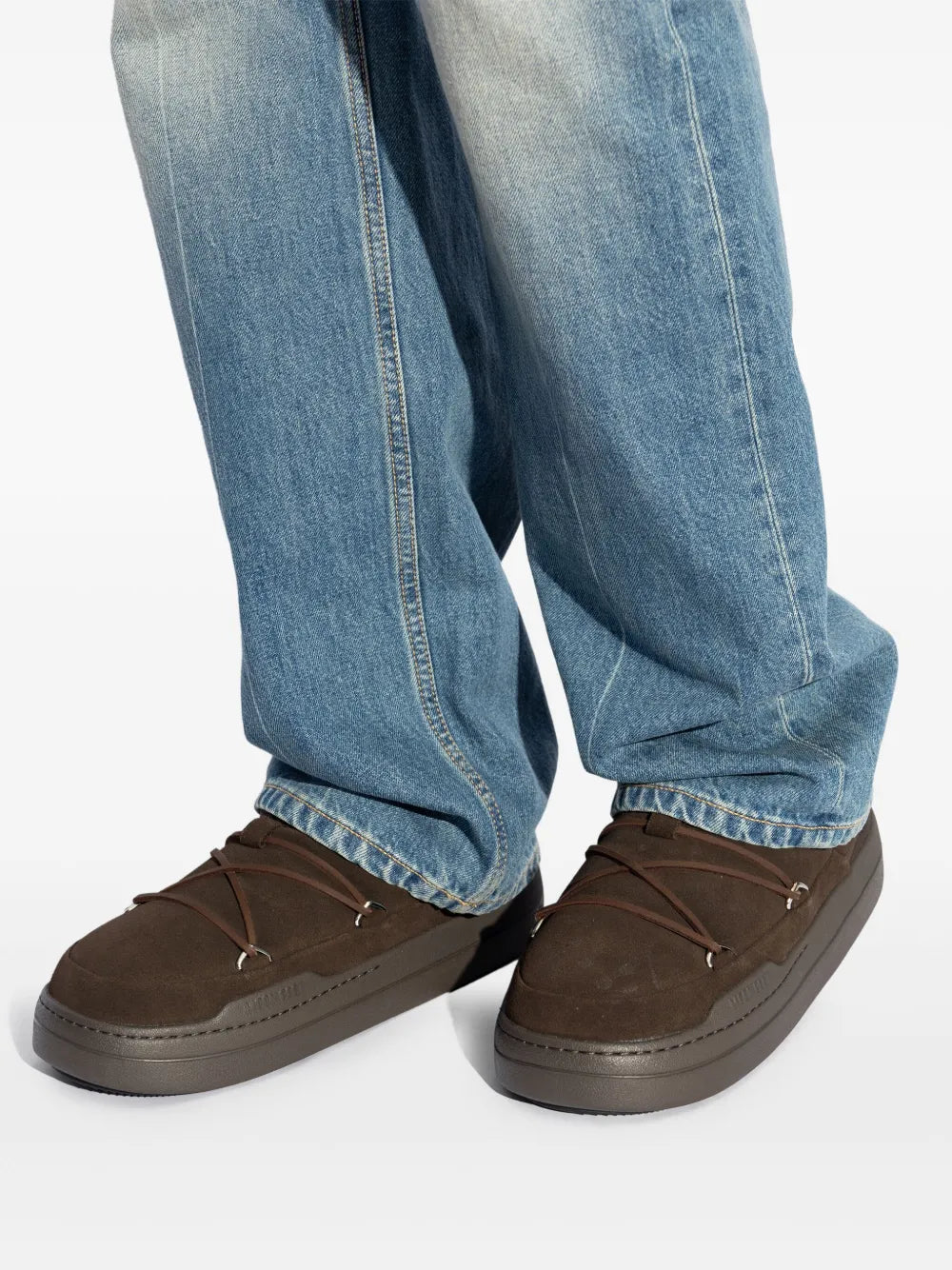 Dark brown high-top sneakers worn with light-wash jeans, side view