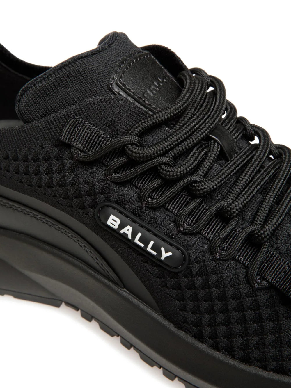 Black sneaker upper close-up with lace threading, hook-and-loop strap, and Bally logo