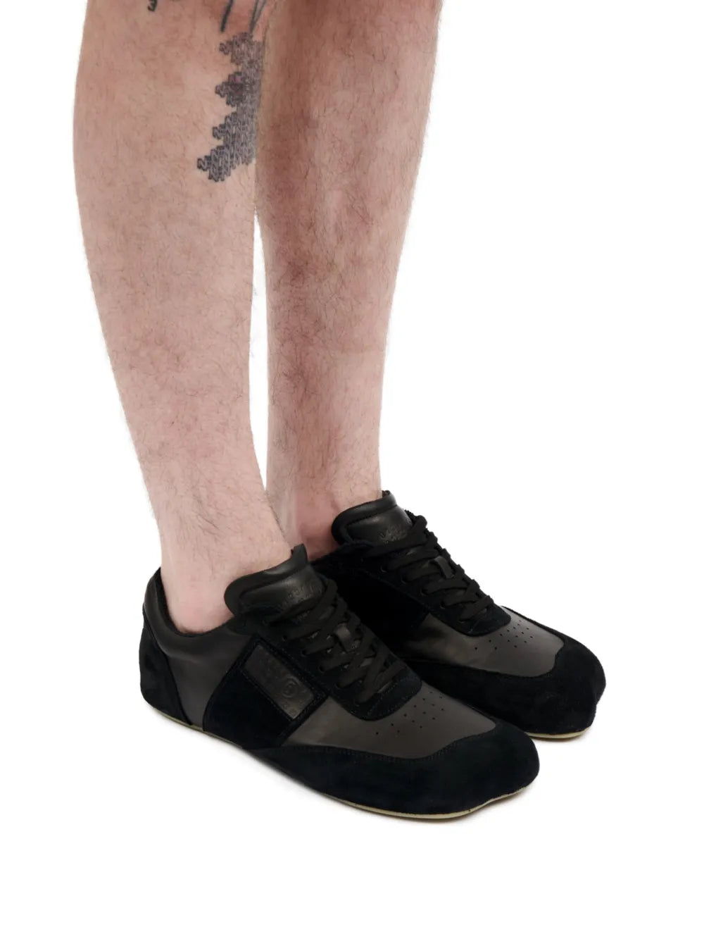 Black MM6 Maison Margiela low-top sneakers being worn, lace-up design