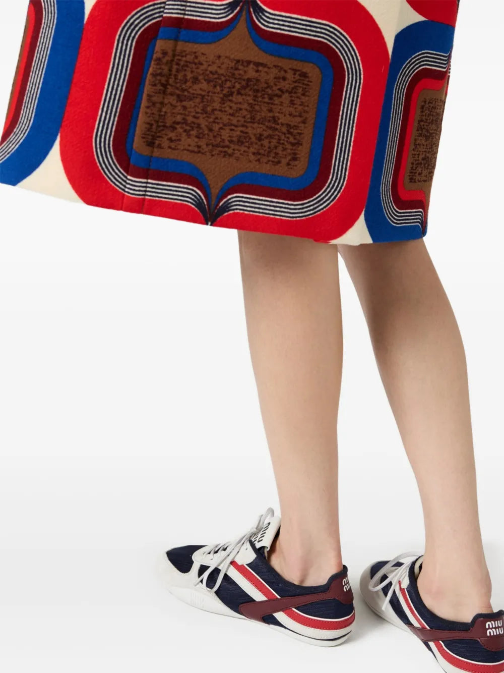 Miu Miu sneakers worn with a patterned skirt, navy and red accents