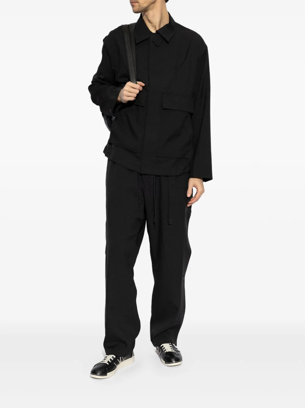 Black low-top sneakers with white laces on model, paired with black outfit