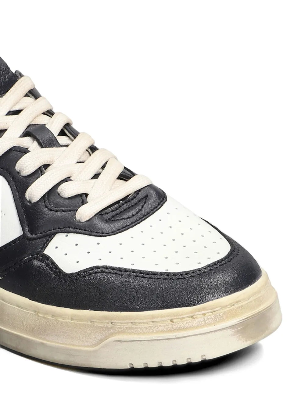 Close-up of black and white lace-up sneakers with perforated toe and textured sole