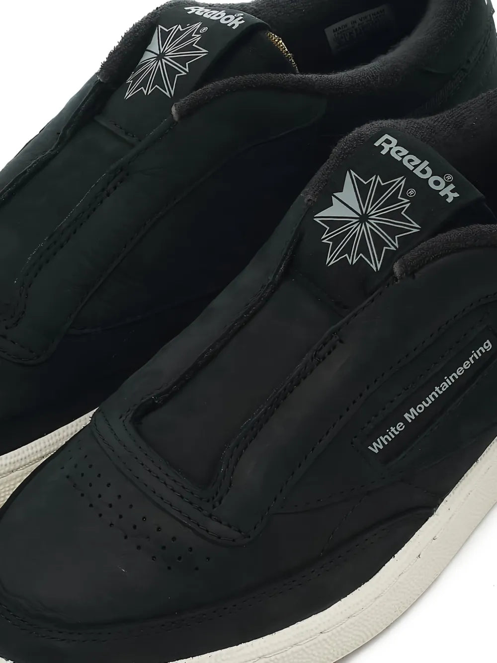 Black sneakers with star logo patches and 'White Mountaineering' text