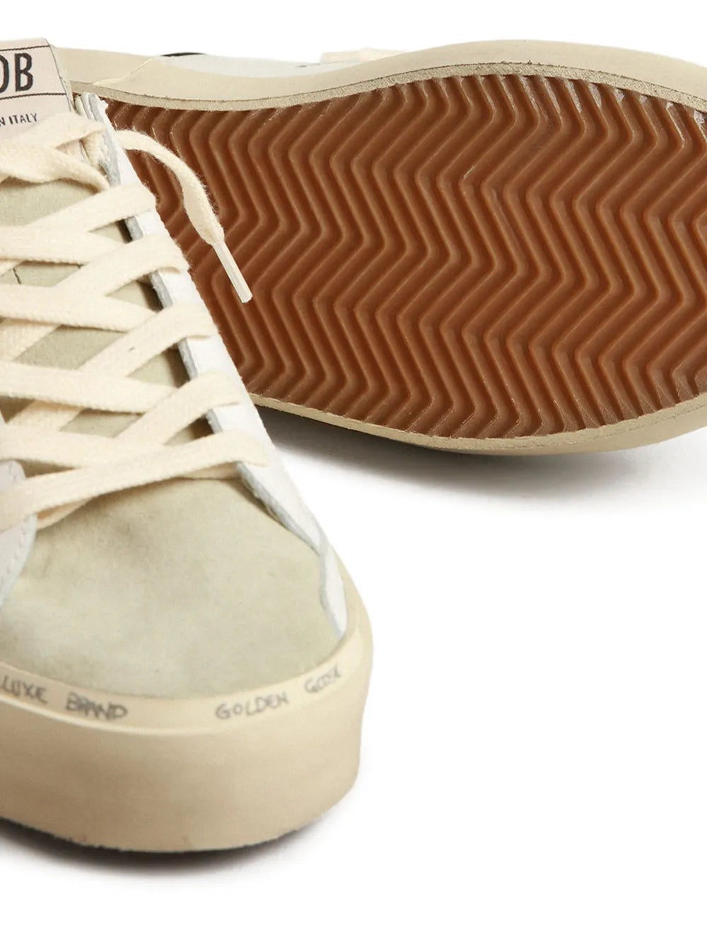 Close-up of white leather sneaker outsole with zigzag tread and cream toe cap