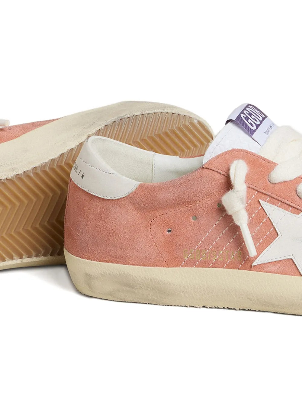 Pink suede sneaker with visible outsole, white side stripe, and lace-up design