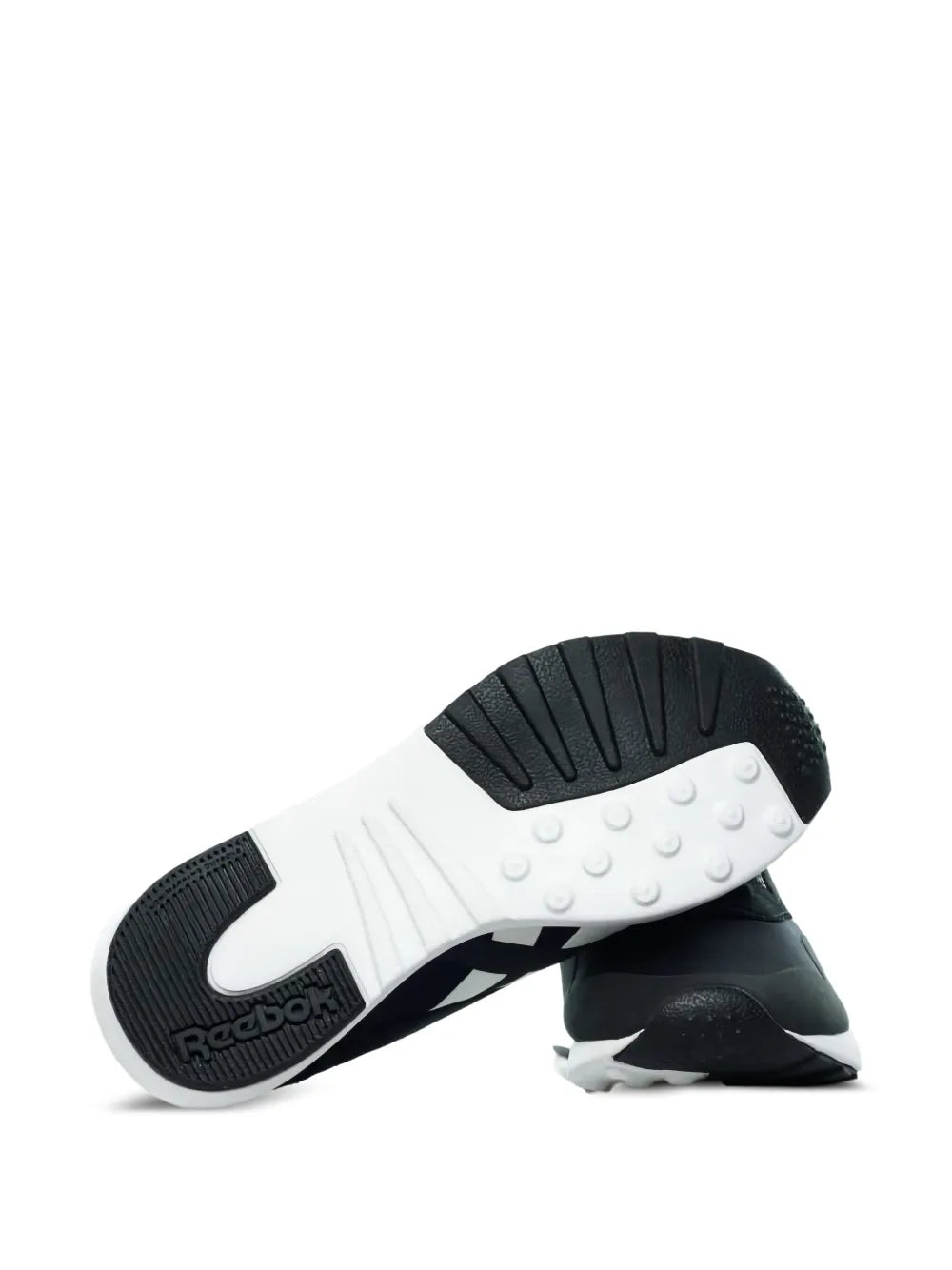Black Reebok trainers outsole view, textured tread and white midsole edge.