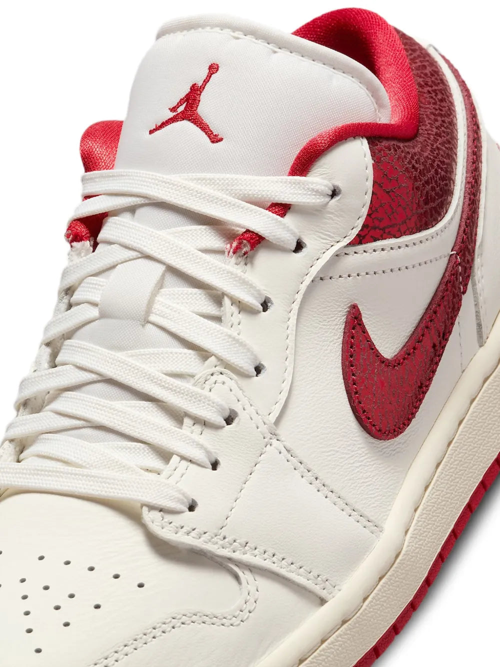Close-up of white leather trainers with red swoosh, white laces, and stitched toe