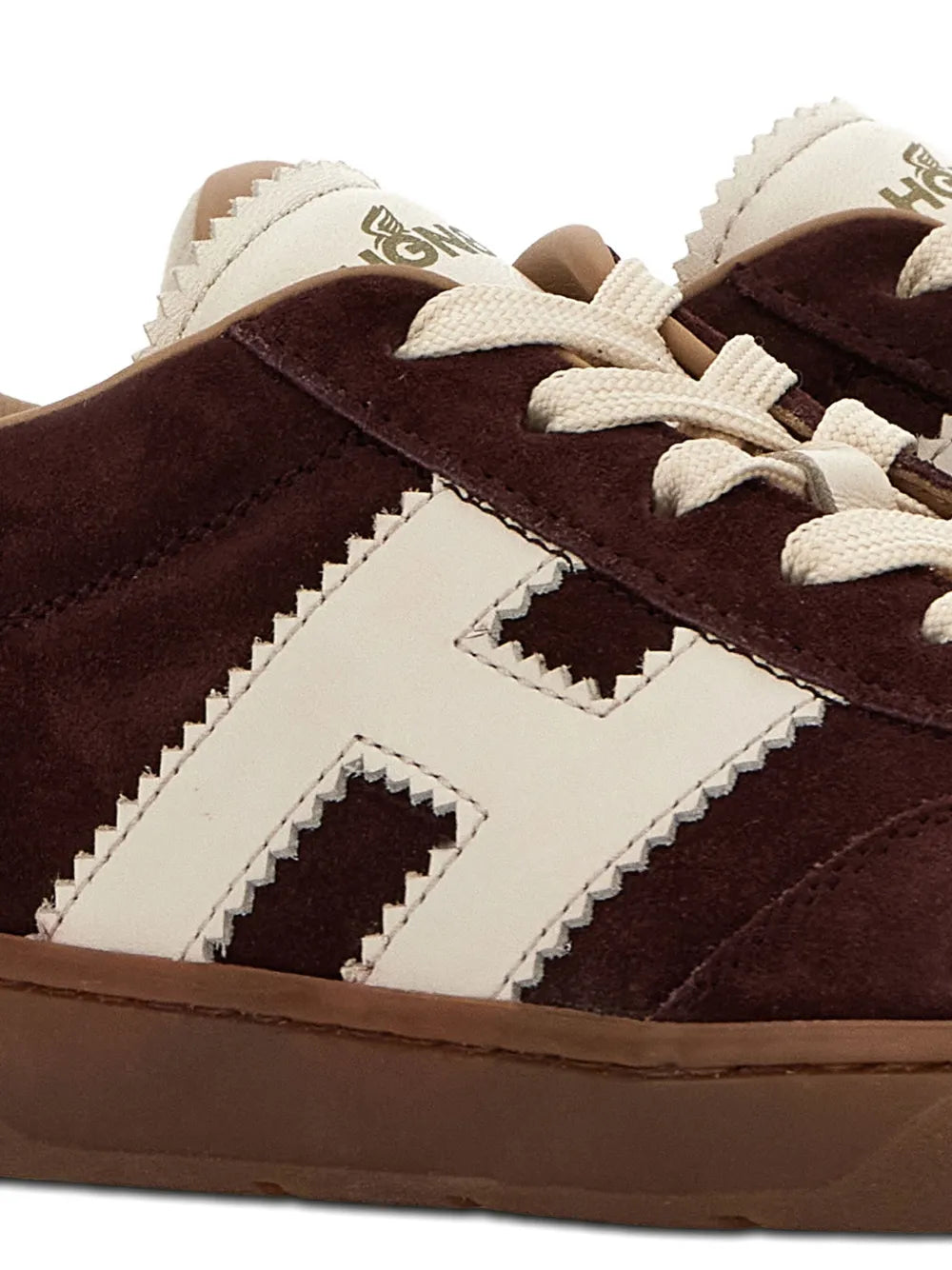 Close-up of brown suede sneakers with white logo panels and laces