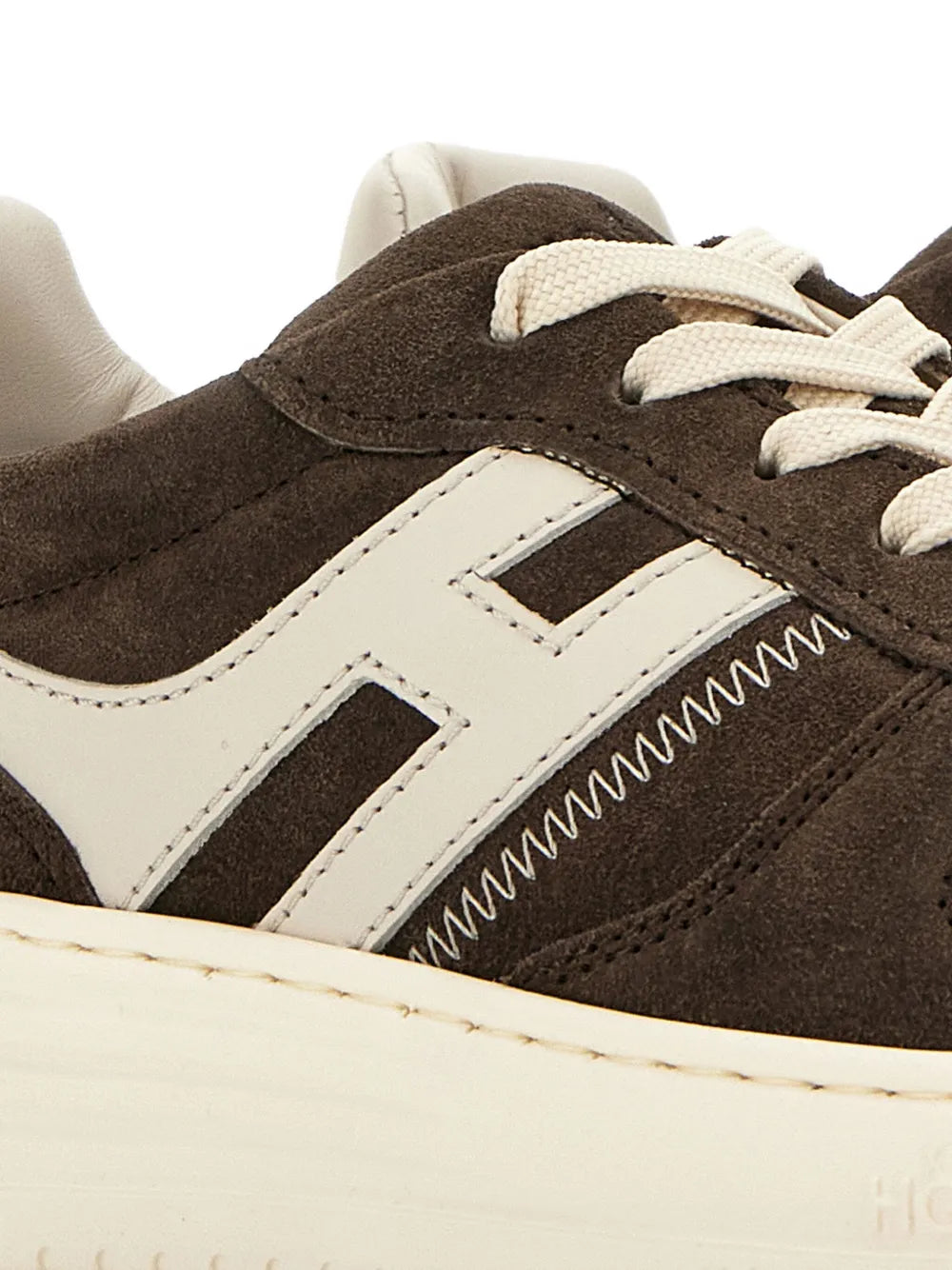 Close-up of coffee-brown sneaker upper with white panel, laces and stitching