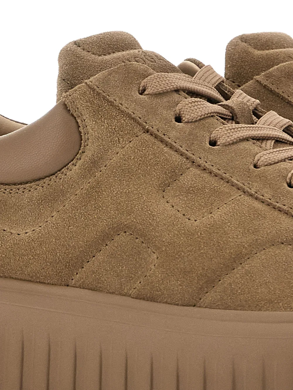 Close-up of brown suede lace-up sneaker with side stitching and textured upper