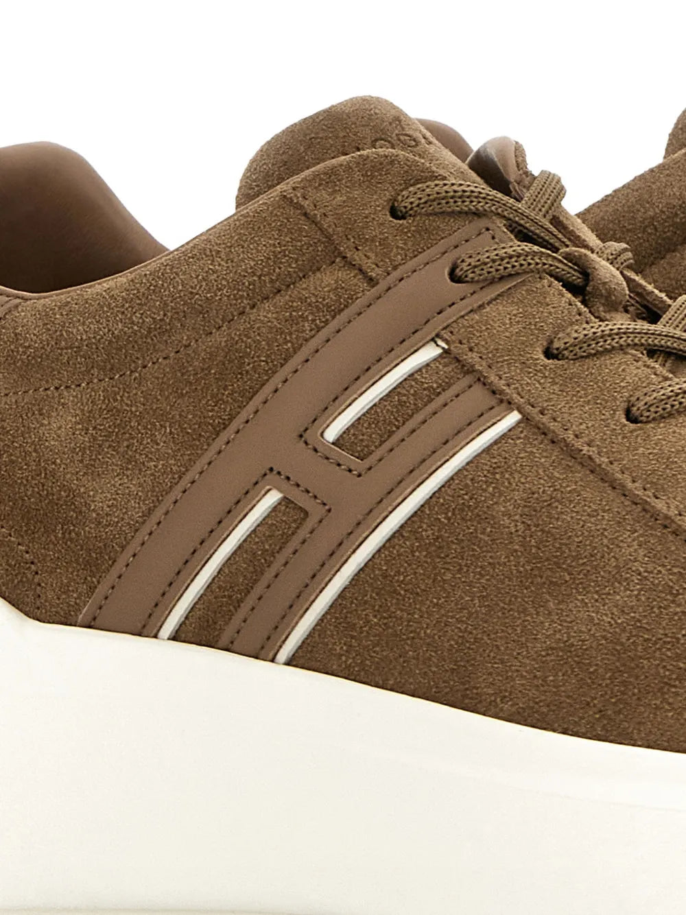 Close-up of earth brown suede sneakers: lace-up, side stripe, white rubber platform sole