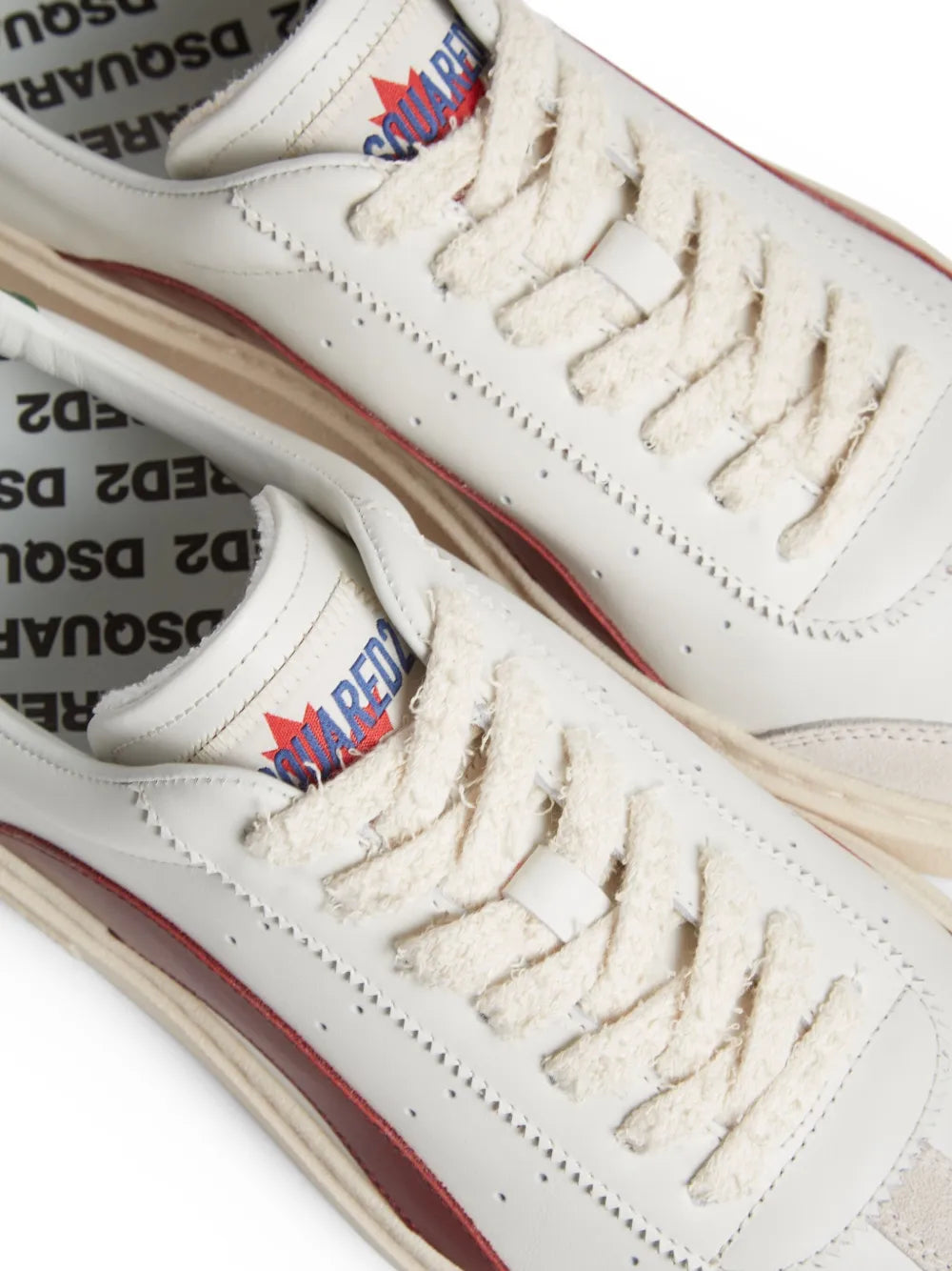 White leather sneakers close-up with multicolor tongue logo and tan sole