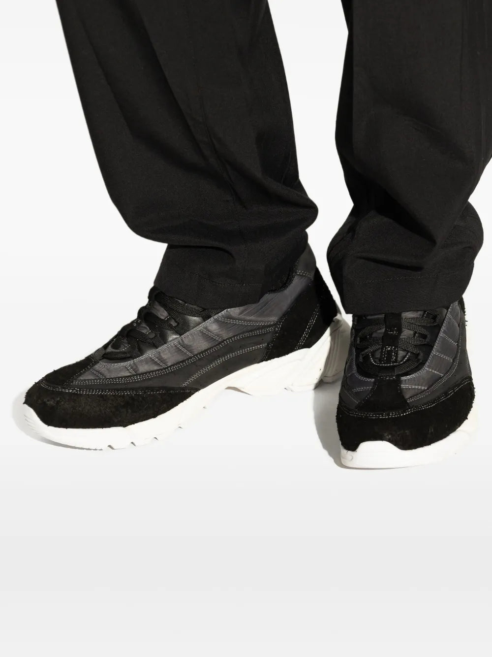 Close-up of black panelled sneakers with lace-up front and white outsole