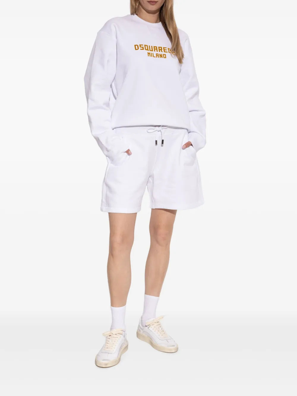 White leather sneakers on model with white socks, lace-up upper and tan sole