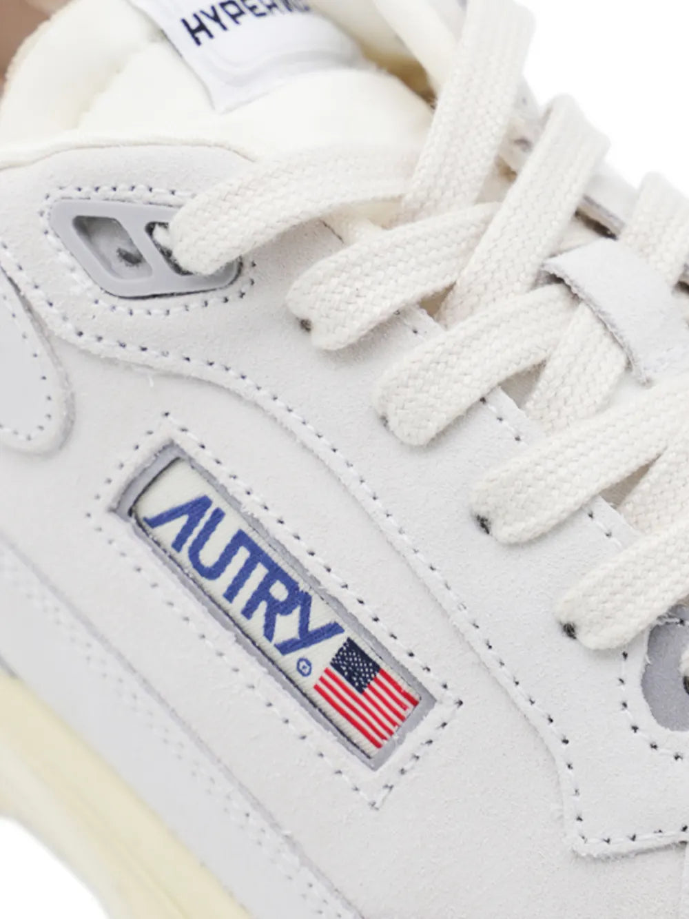 White sneaker with embroidered Autry logo patch, white laces, and lace-eyelet details