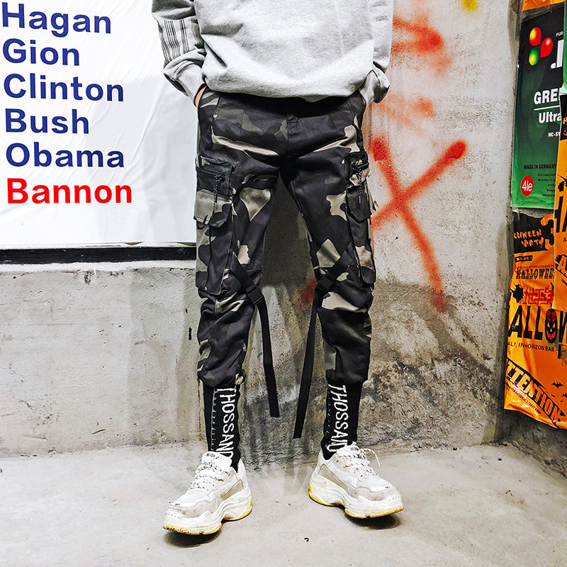 Black cargo straight-bottom pants with multiple flap pockets and long tie straps at sides