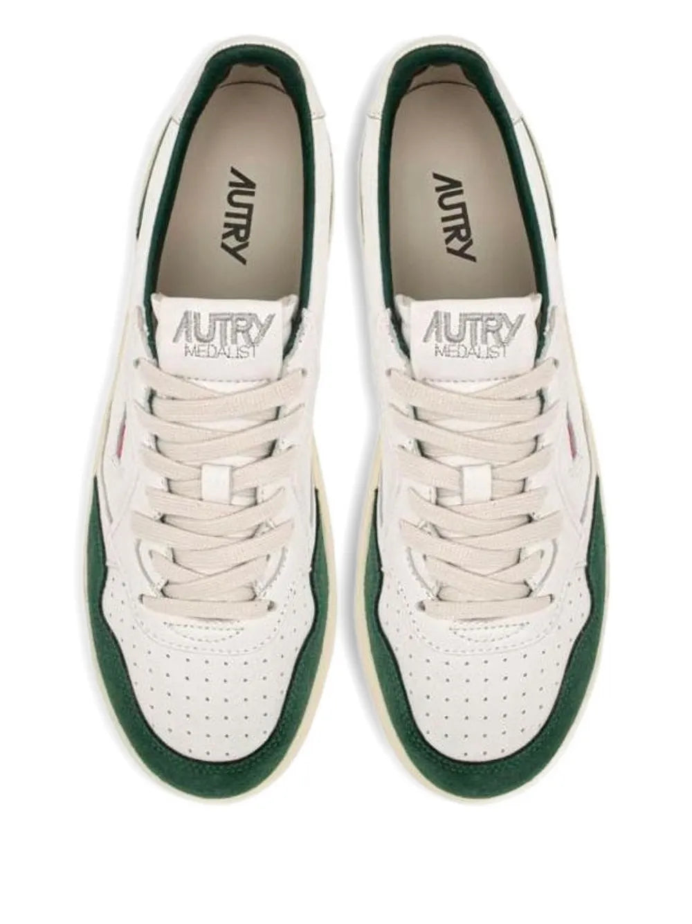 White low-top sneakers with green trim, perforated toe, and AUTRY MEDALIST logos