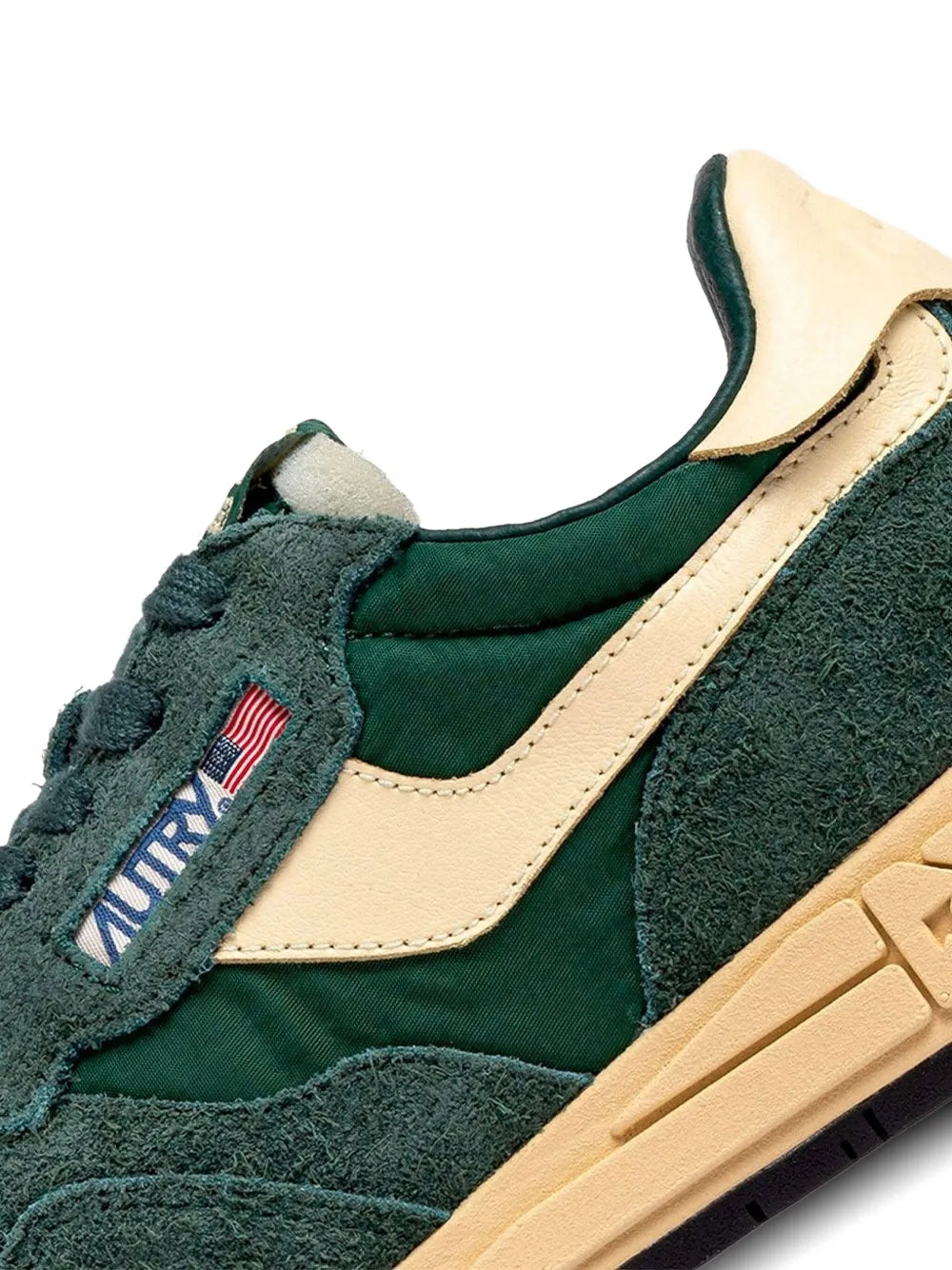 Close-up of green suede sneakers with beige side panel, laces, and tan textured sole