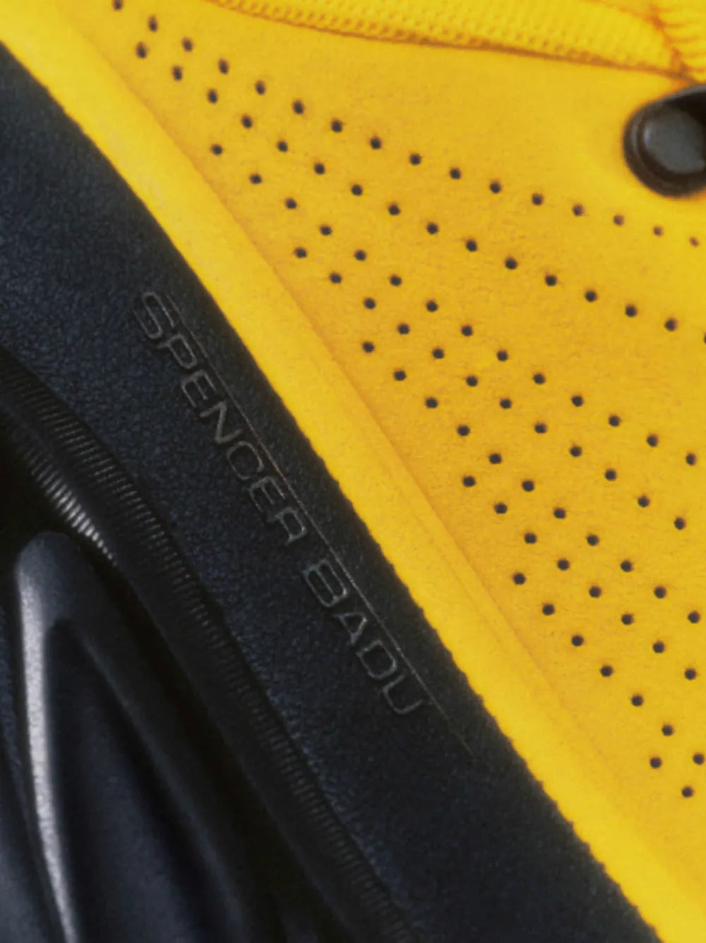 Close-up of yellow perforated upper with 'Super' branding on black side stripe