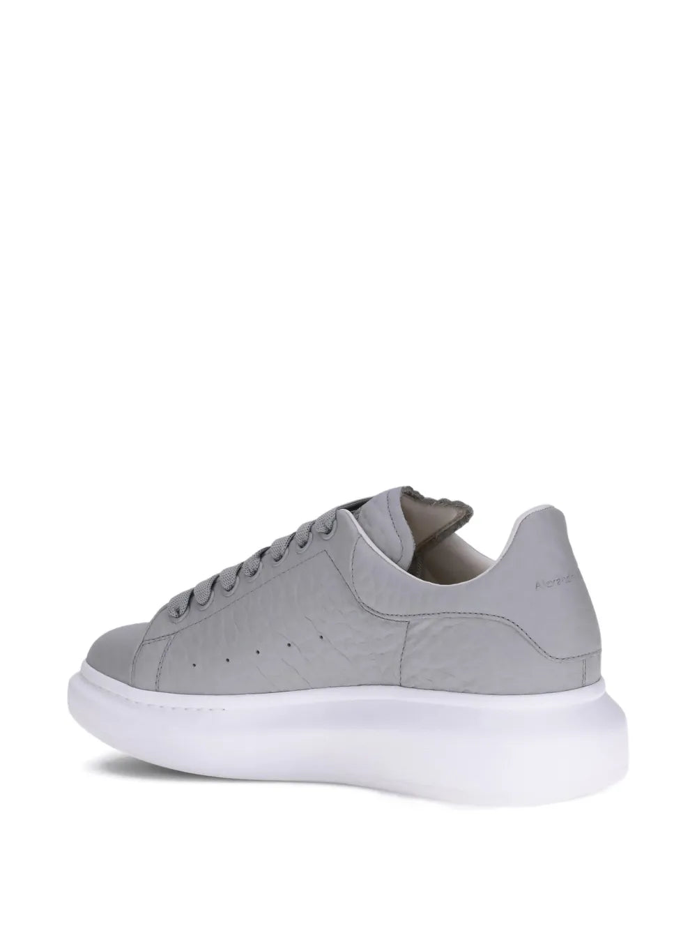 Grey low-top sneakers, rear 3/4 view, with white rubber sole