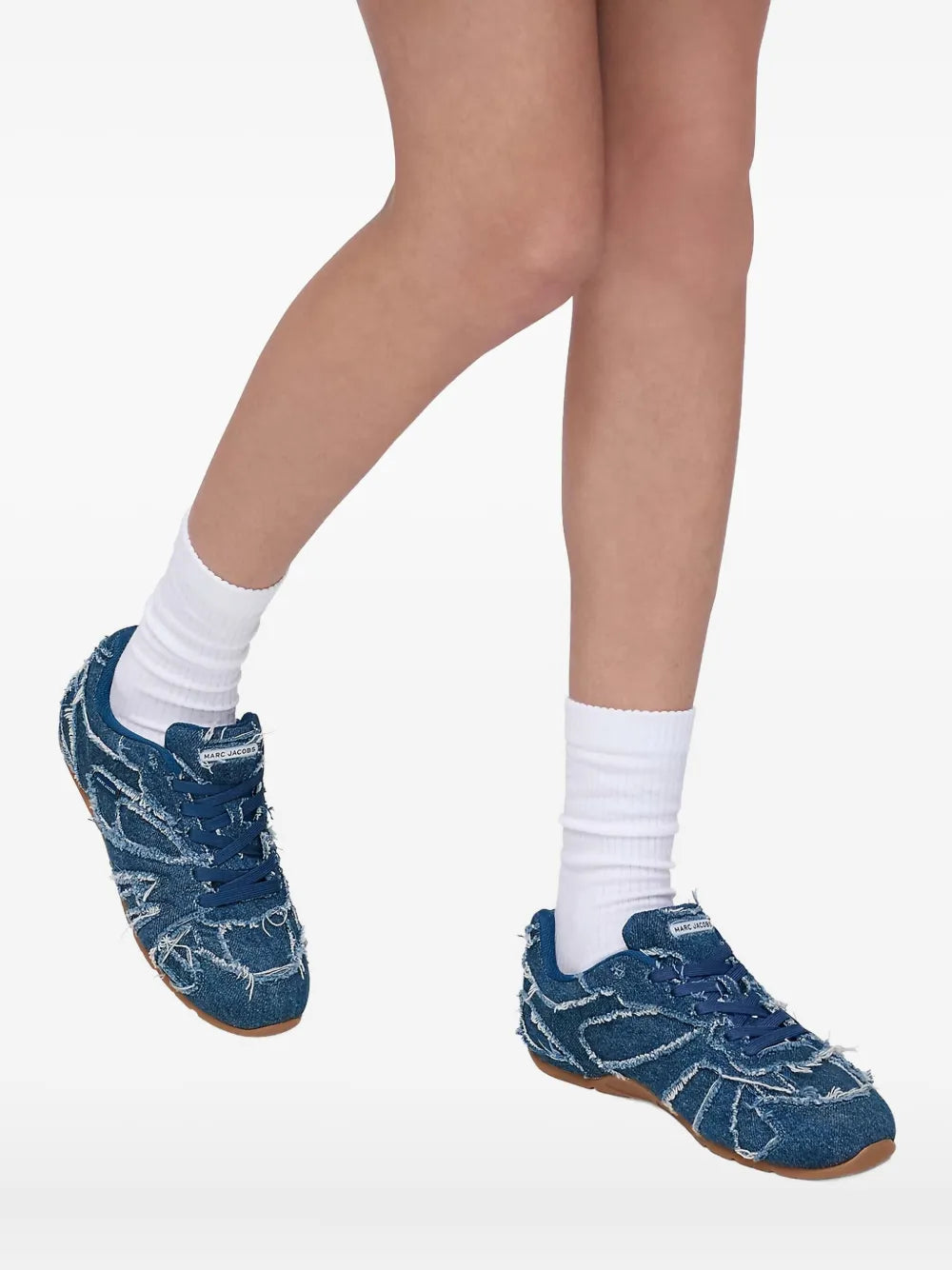 Blue denim lace-up sneakers worn with white socks, gum sole