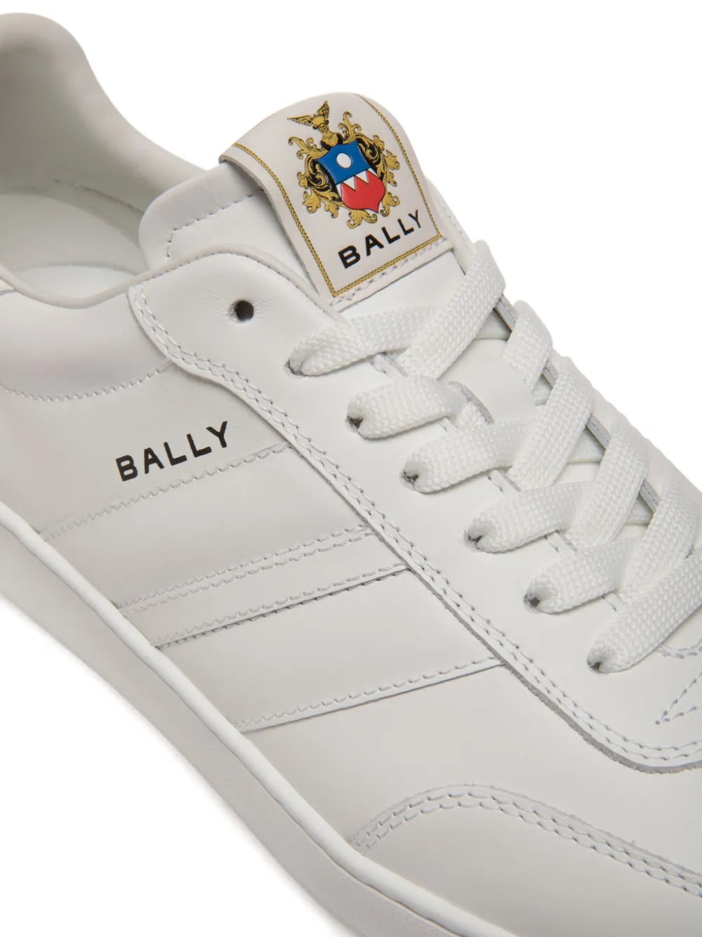 White Bally sneakers close-up: crest tongue patch and lace-up eyelets