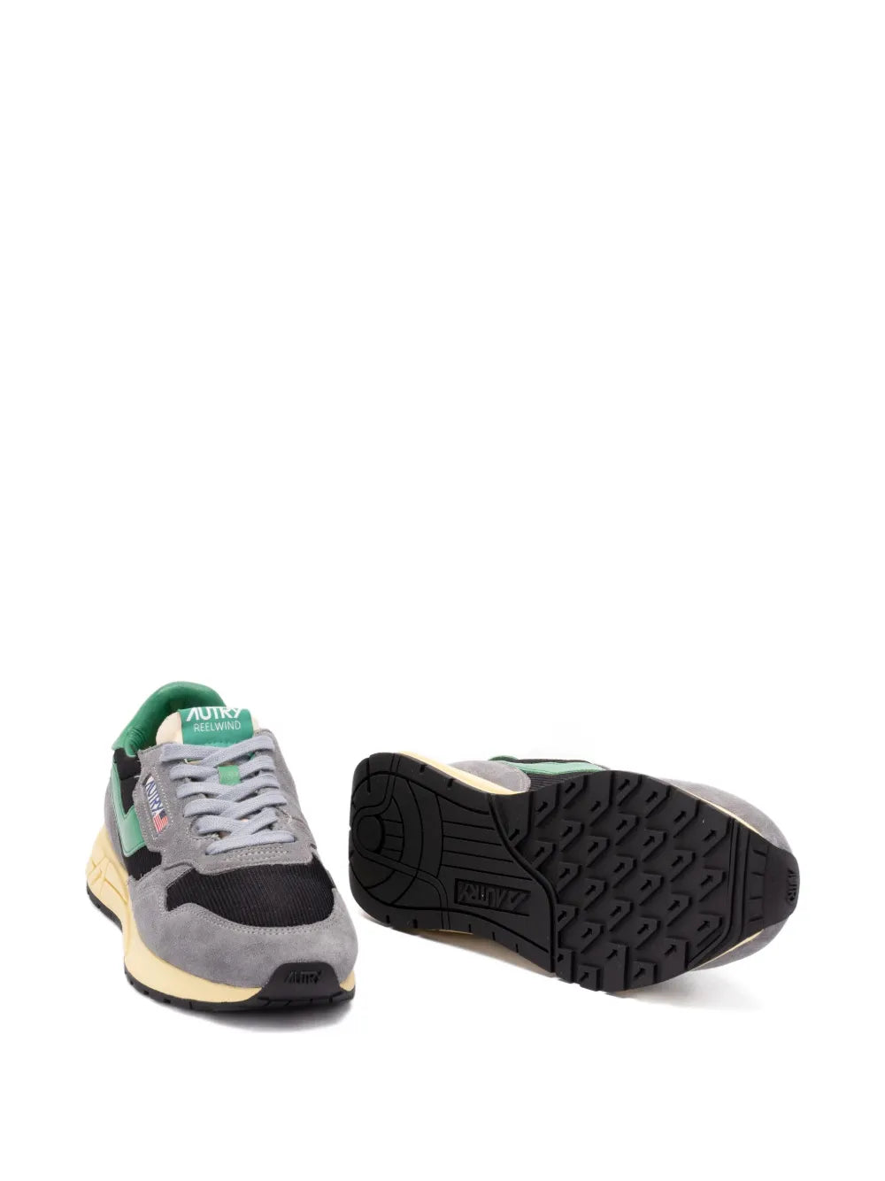 Grey low-top sneakers outsole view with tread, green heel detail and gum midsole.