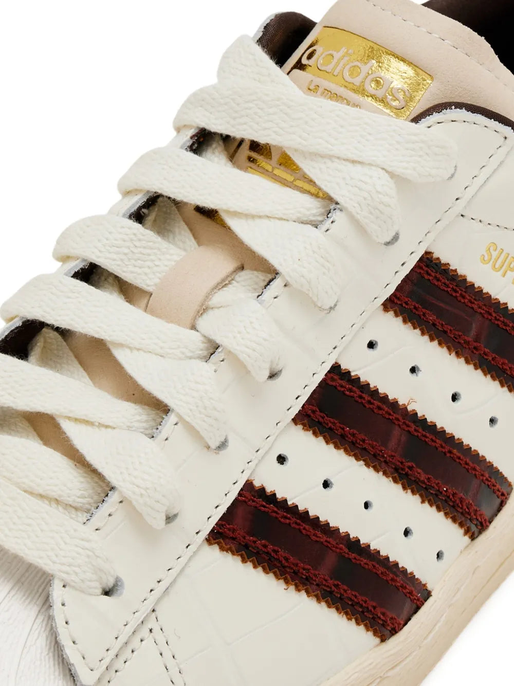 Close-up of adidas Superstar sneaker laces and brown striped shell toe