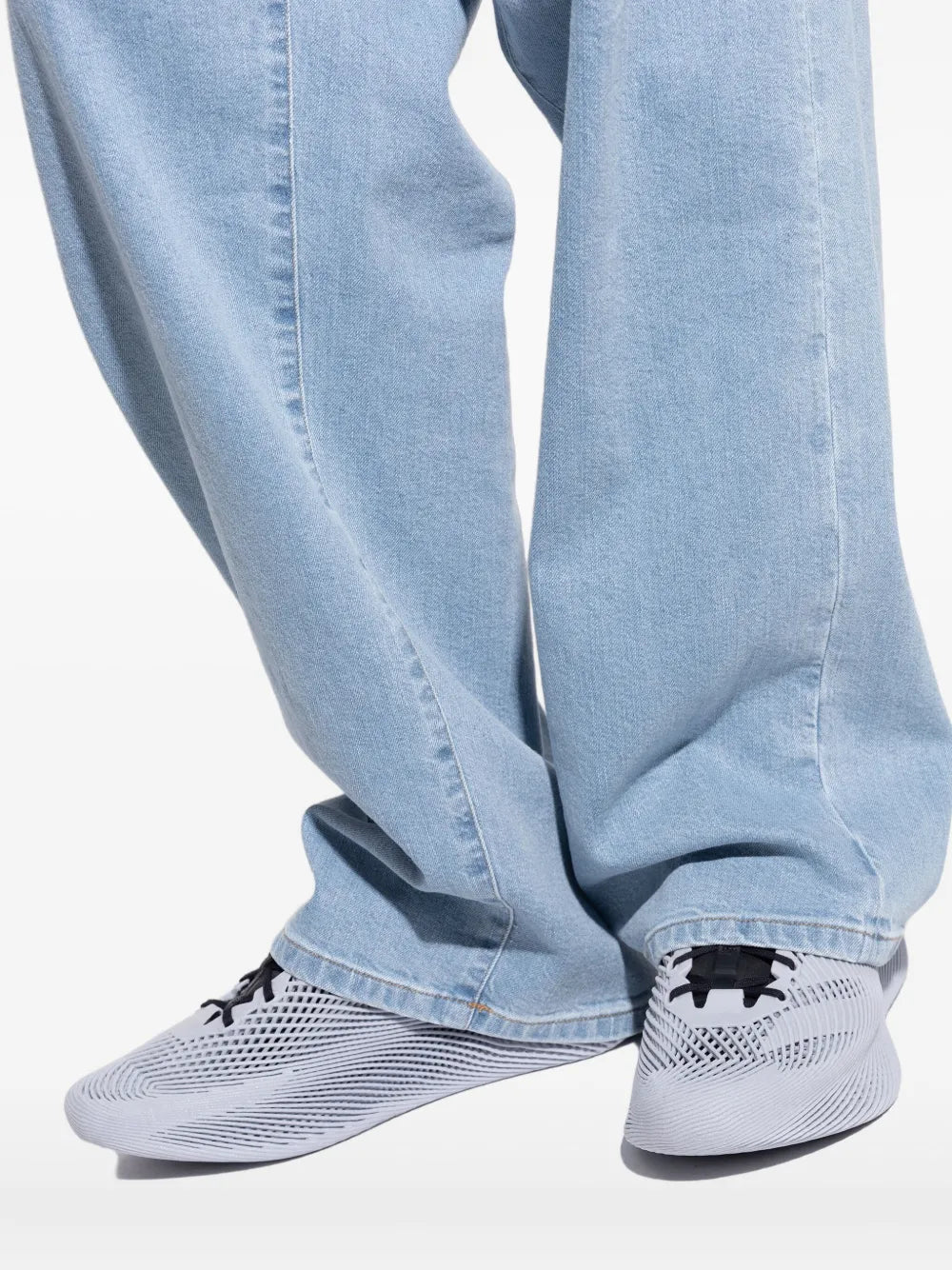Grey low-top mesh sneakers with black laces and lattice pattern worn with light denim