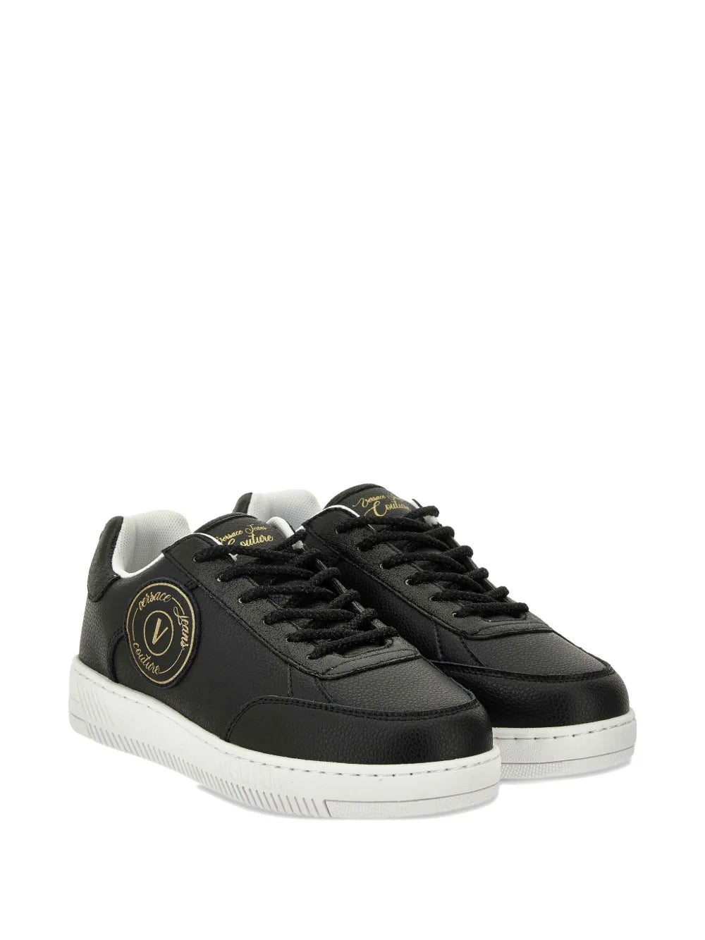 Black pair of low-top lace-up sneakers with gold logo patch and white rubber sole